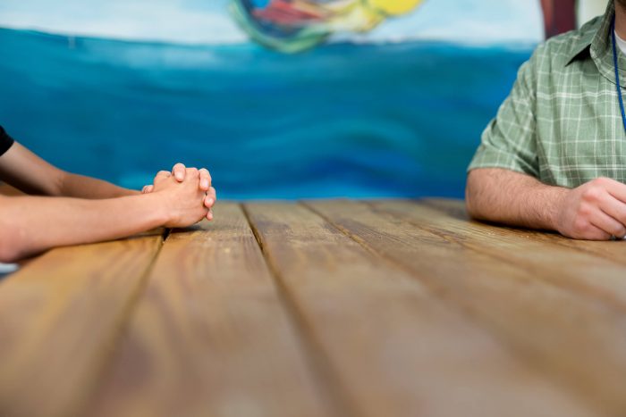 Two people sitting at a table, one with hands crossed